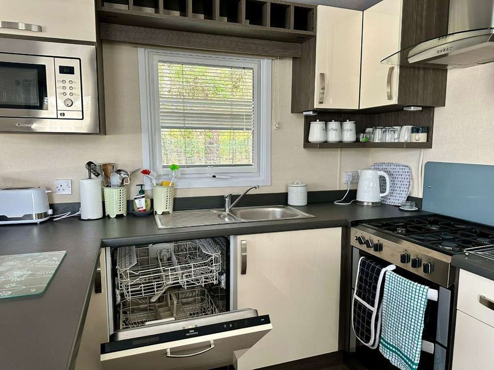 A kitchen with a sink, oven, and dishwasher at 2Bed Ringwood Cabin incl Park Pass SelfCheckin, Saint Leonards near Ferndown