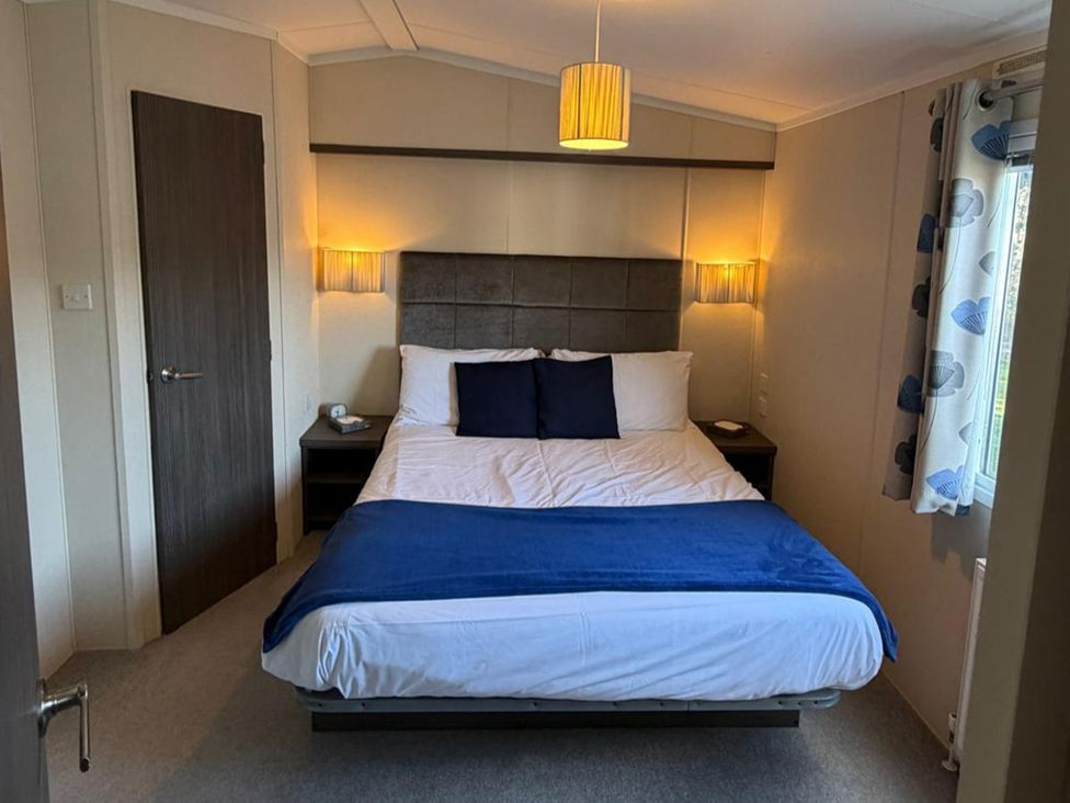 A bedroom with a bed and nightstand at 2Bed Ringwood Cabin incl Park Pass SelfCheckin Saint Leonards near Ferndown