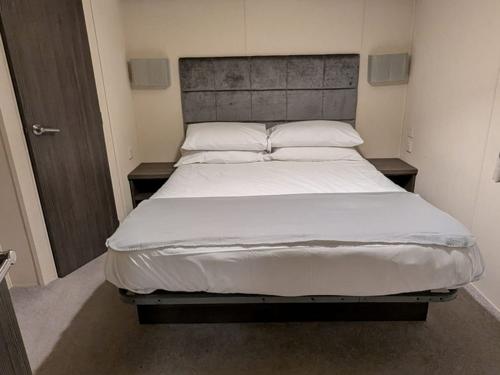 A bedroom with a bed and bedside table at 2Bed Ringwood Cabin incl Park Pass SelfCheckin Saint Leonards near Ferndown