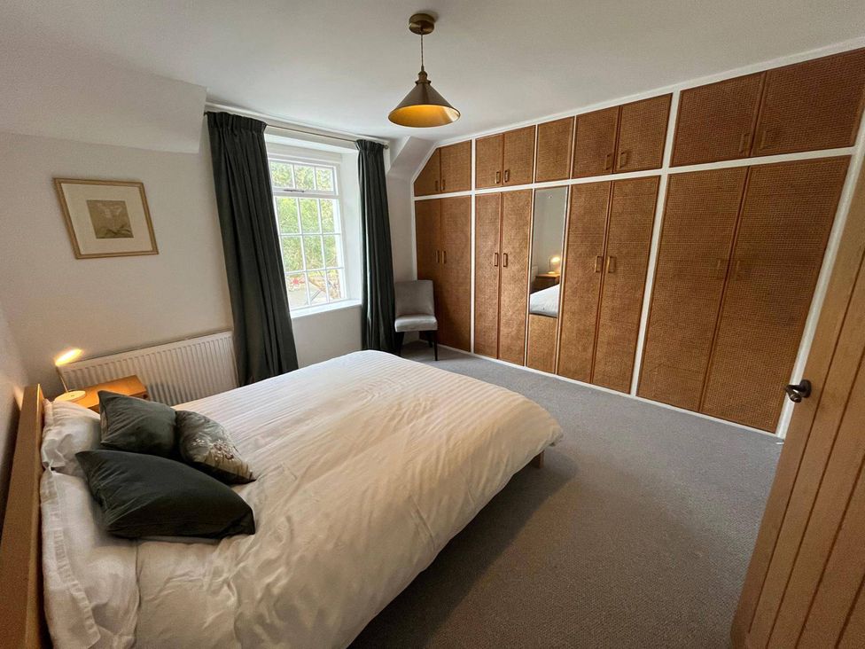 A bedroom with a bed and wardrobe at Charming 3Bed Cottage  Private Garden Parking in Torquay