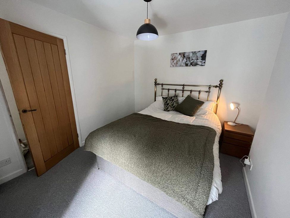 A bedroom with a bed and nightstand at Charming 3Bed Cottage Private Garden Parking in Torquay