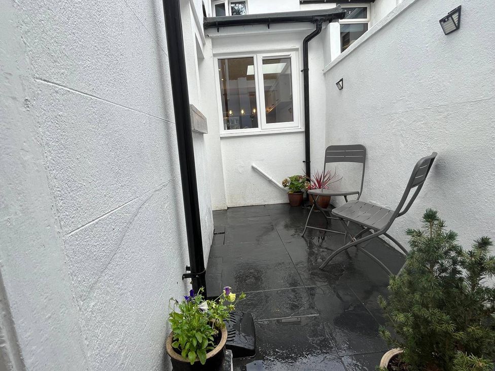 An outdoor area with a chair and plants at Charming 3Bed Cottage Private Garden Parking in Torquay