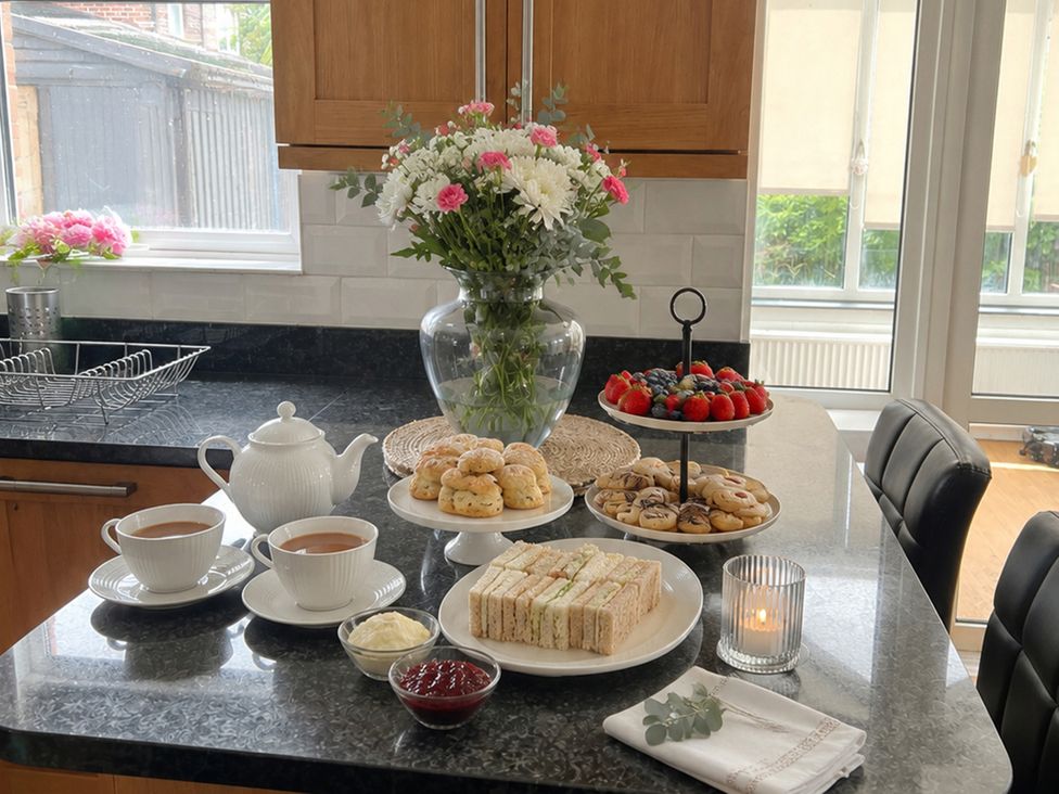 A kitchen with tea, scones, sandwiches, and fruit on the counter at 3Bed House Sleeps 7 Parking Garden Pets Ok, Lytham St. Annes