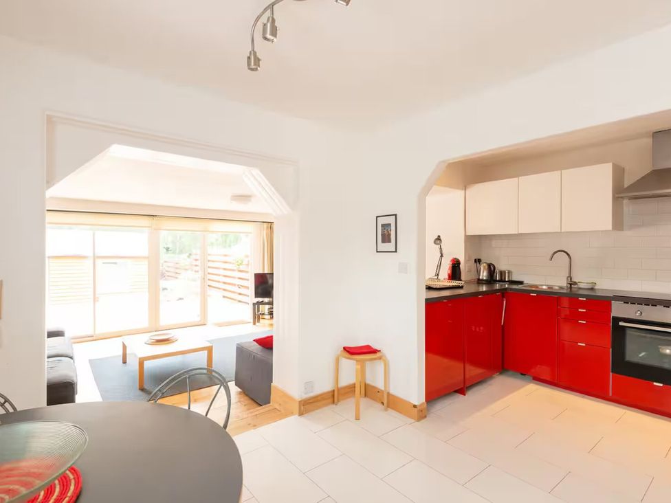A kitchen with red cabinets and a table at 2bed Cottage Private garden Freeparking in Aviemore