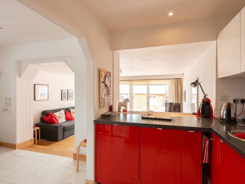 A kitchen with a red unit and a view of the living area at 2bed Cottage Private garden Freeparking, Aviemore