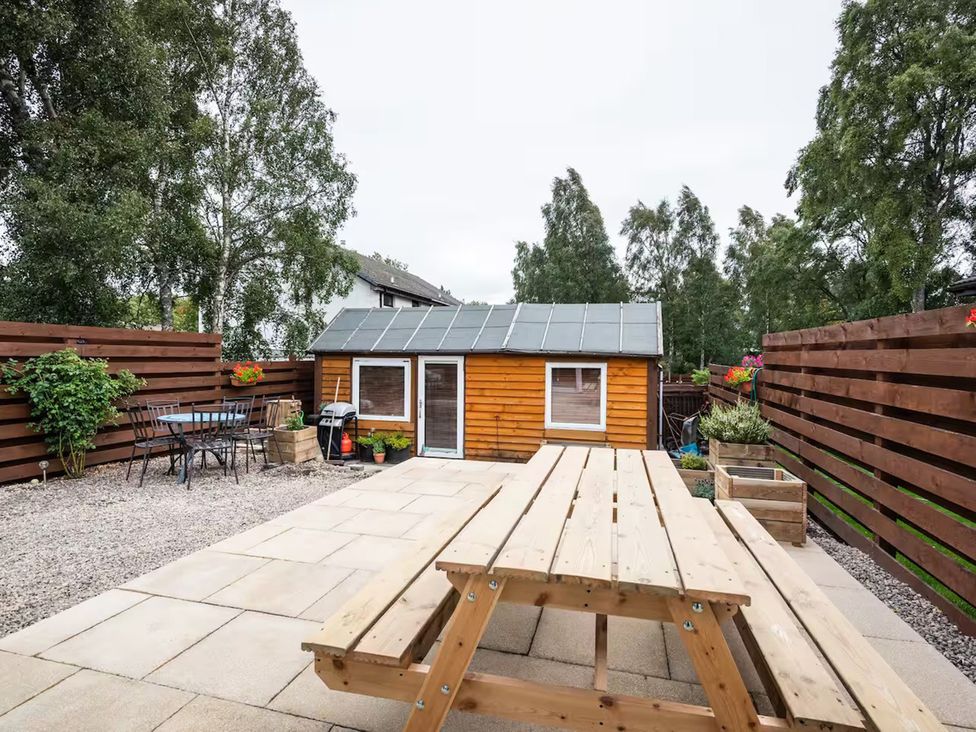 A garden with a picnic table, chairs, and a shed at 2bed Cottage Private garden Freeparking in Aviemore