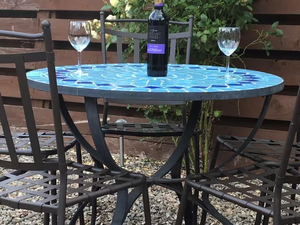 A round table with wine glasses and a bottle at 2bed Cottage Private garden Freeparking in Aviemore