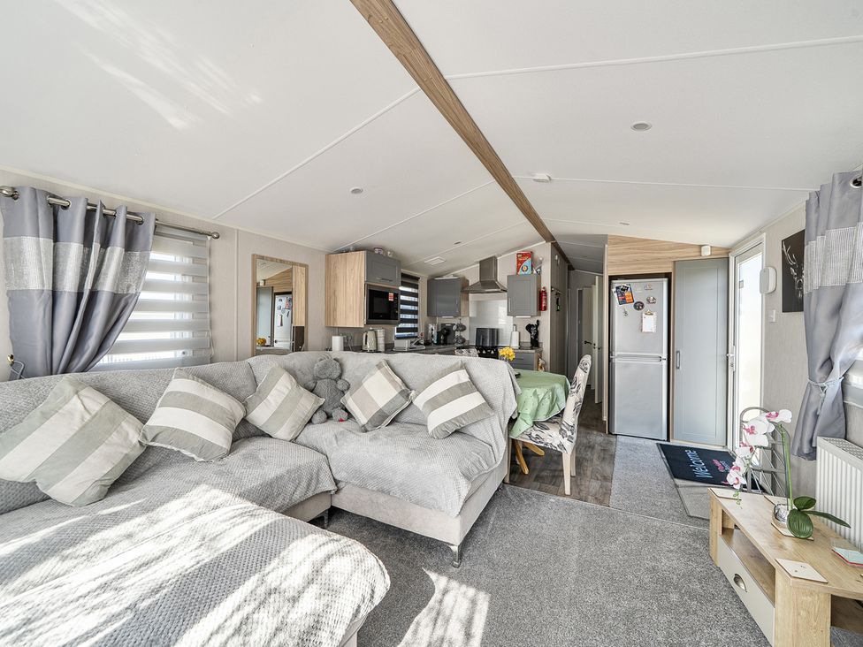 A living room with a sofa, dining area, and kitchen units at Cayton Bay Holiday Park Kestrel40 in Cayton Bay