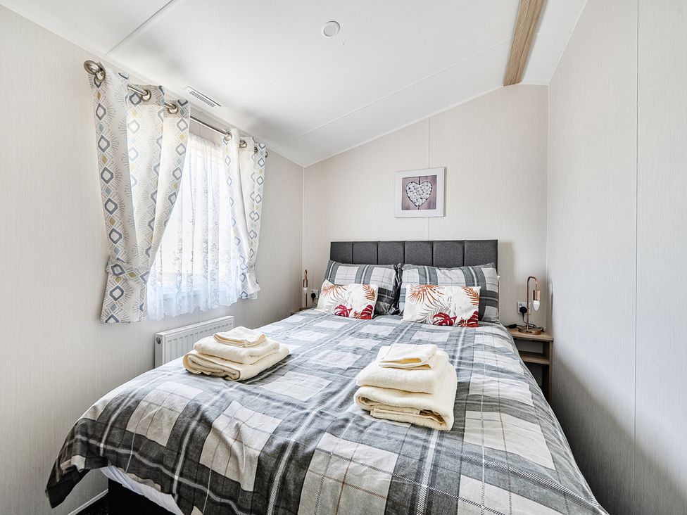 A bedroom with a double bed and decorative pillows at Cayton Bay Holiday Park Kestrel40, Cayton Bay