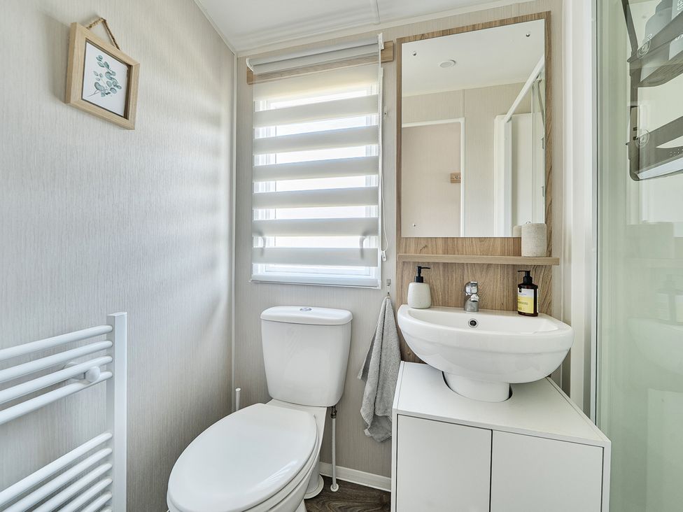 A bathroom with a toilet, sink, and mirror at Cayton Bay Holiday Park Kestrel40, Cayton Bay
