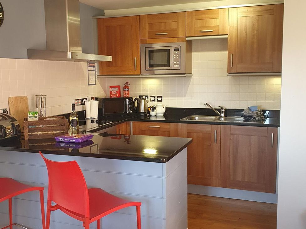 A kitchen with wooden cabinets and appliances at 2bed sleeps4 pool freeparking Trenythonestate Near Par