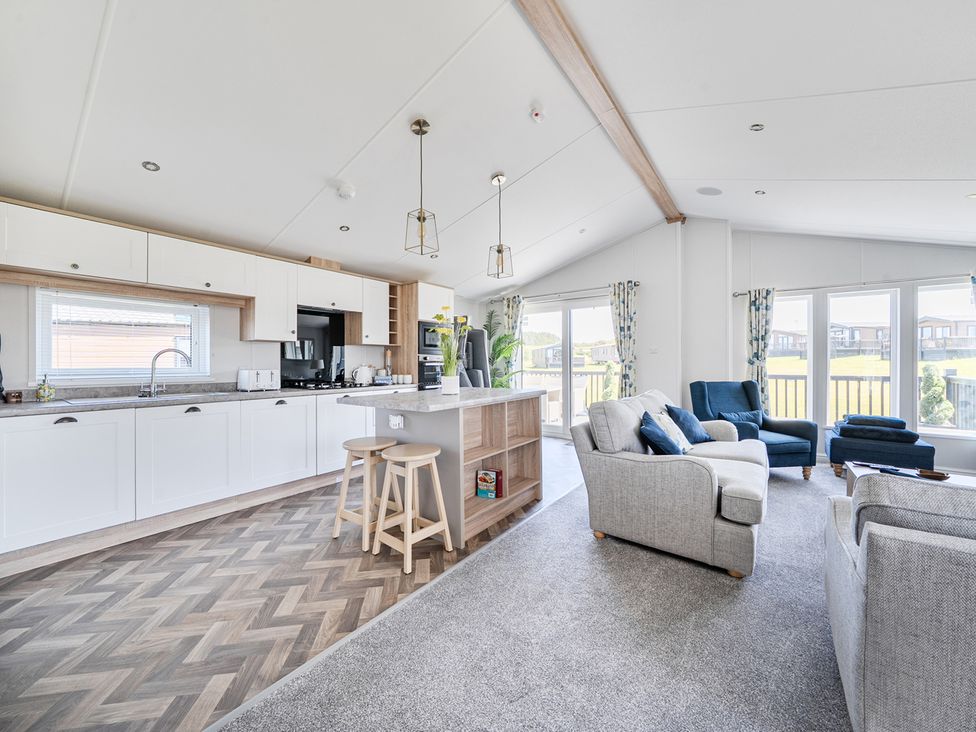A kitchen with bar stools and living area at Atlantic Breeze Luxury Lodge sleep 6 Mullacott near Ilfracombe