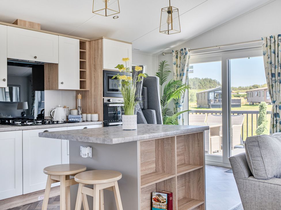 A kitchen with stools and appliances at Atlantic Breeze Luxury Lodge sleep 6 Mullacott near Ilfracombe