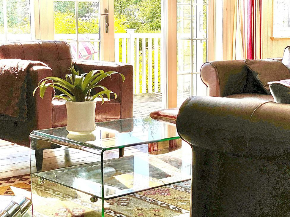 A living room with a glass table and brown armchair at Stunning Sleeps 6 Luxury Lodge Pets Mercia Marina near Willington, Derbyshire