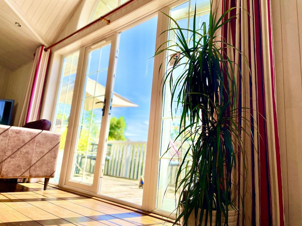 A living room with sliding glass doors and a plant at Stunning Sleeps 6 Luxury Lodge Pets Mercia Marina near Willington, Derbyshire