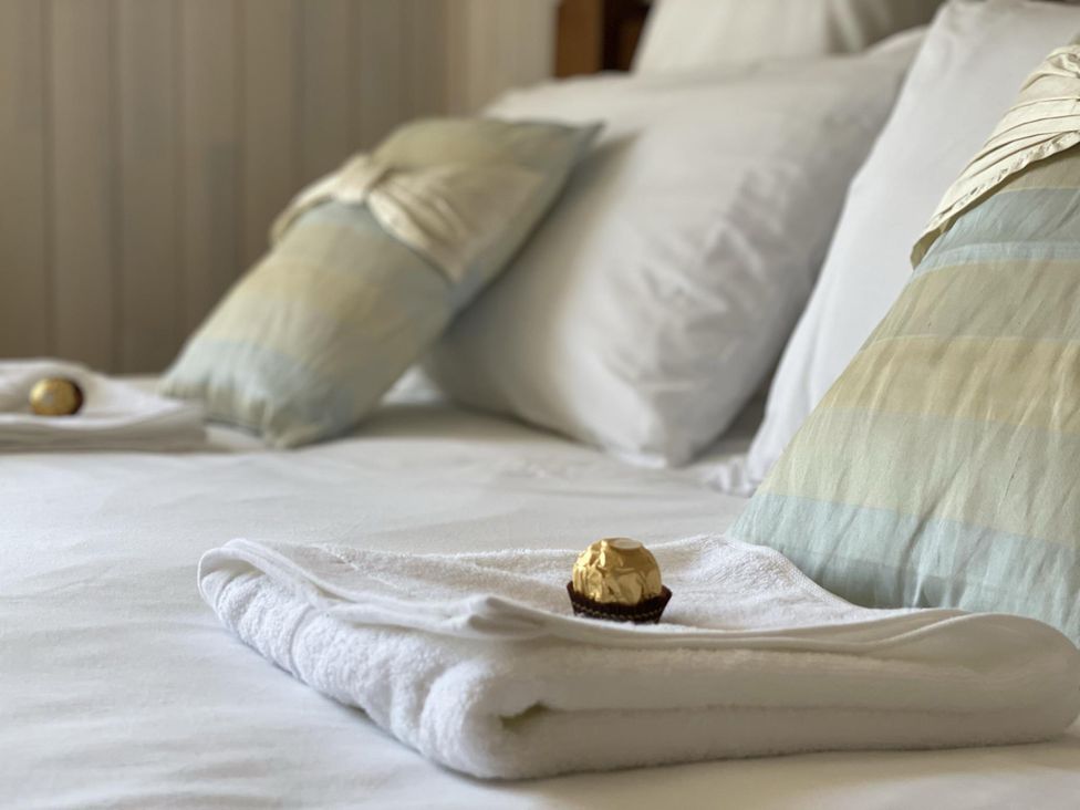 A bed with pillows and towels at Stunning Sleeps 6 Luxury Lodge Pets Mercia Marina near Willington, Derbyshire