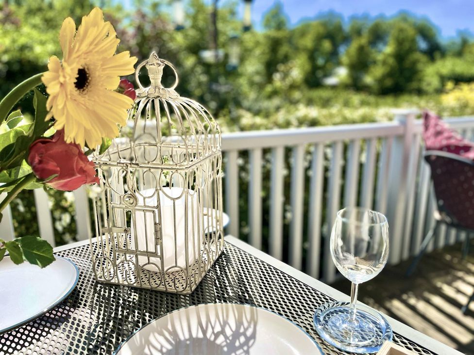 A table set with flowers, a candle holder, and glassware at Stunning Sleeps 6 Luxury Lodge Pets Mercia Marina near Willington, Derbyshire