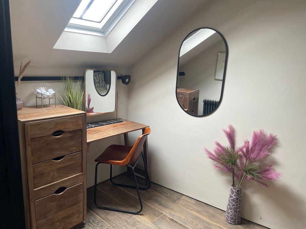 An office with a desk, mirror, chair, and plants