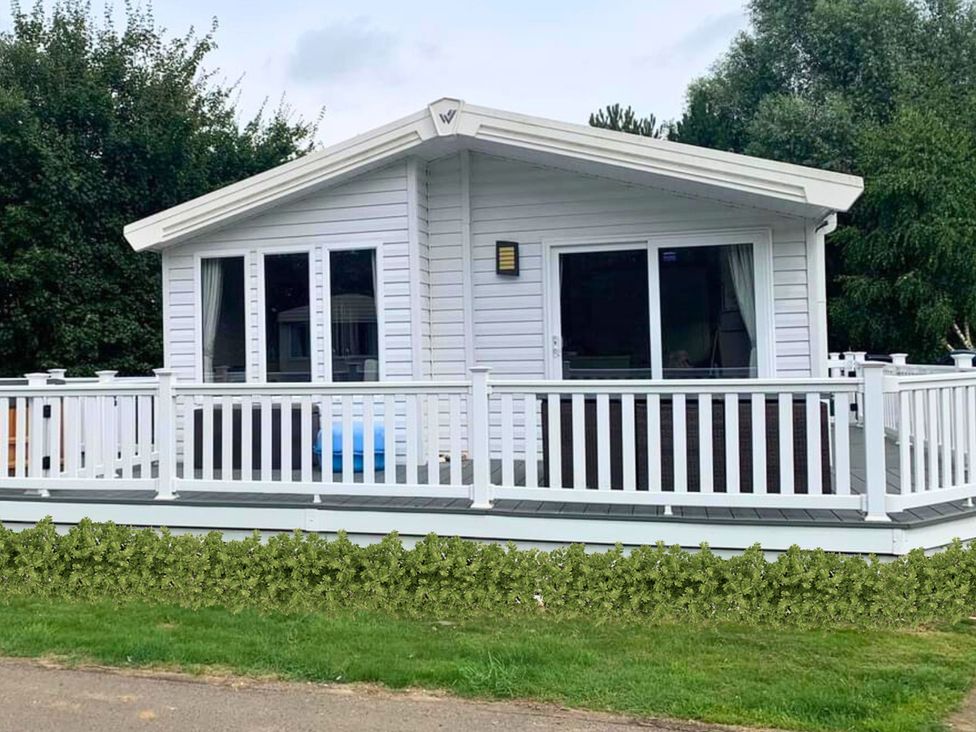A cabin with a deck and windows at Meadows 33 Hot tub Southview Holiday Park in Skegness