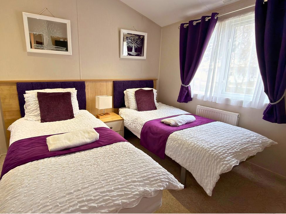 A bedroom with two beds and a nightstand at Meadows 33 Hot tub Southview Holiday Park Skegness