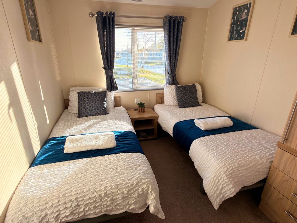 A bedroom with two beds and a nightstand at Sunset 19 Southview Holiday Park Skegness