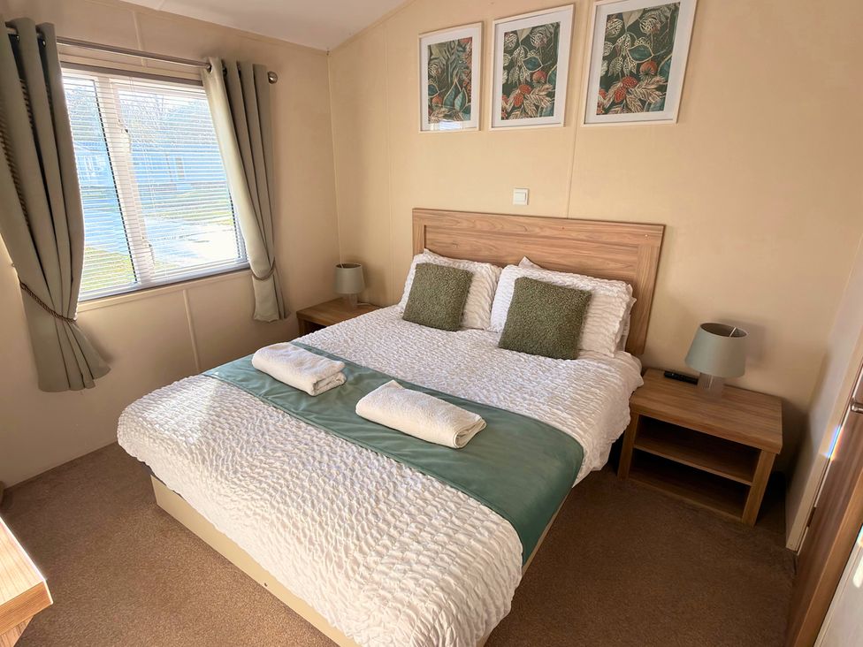 A bedroom with a bed and bedside tables at Sunset 19 Southview Holiday Park Skegness