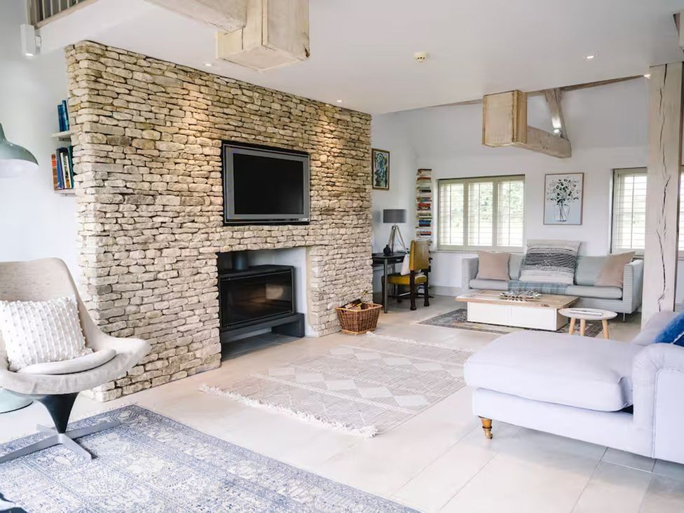 A living room with a rock wall and fireplace at Stunning 6 Bedroom Riverside Barn Cotswold Mill in Ewan near Kemble