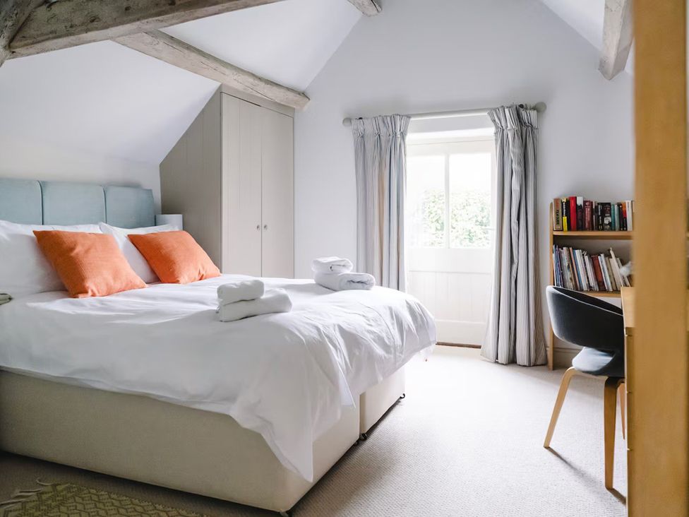 A bedroom with a bed and bookshelf at Stunning 6 Bedroom Riverside Barn Cotswold Mill Ewan near Kemble