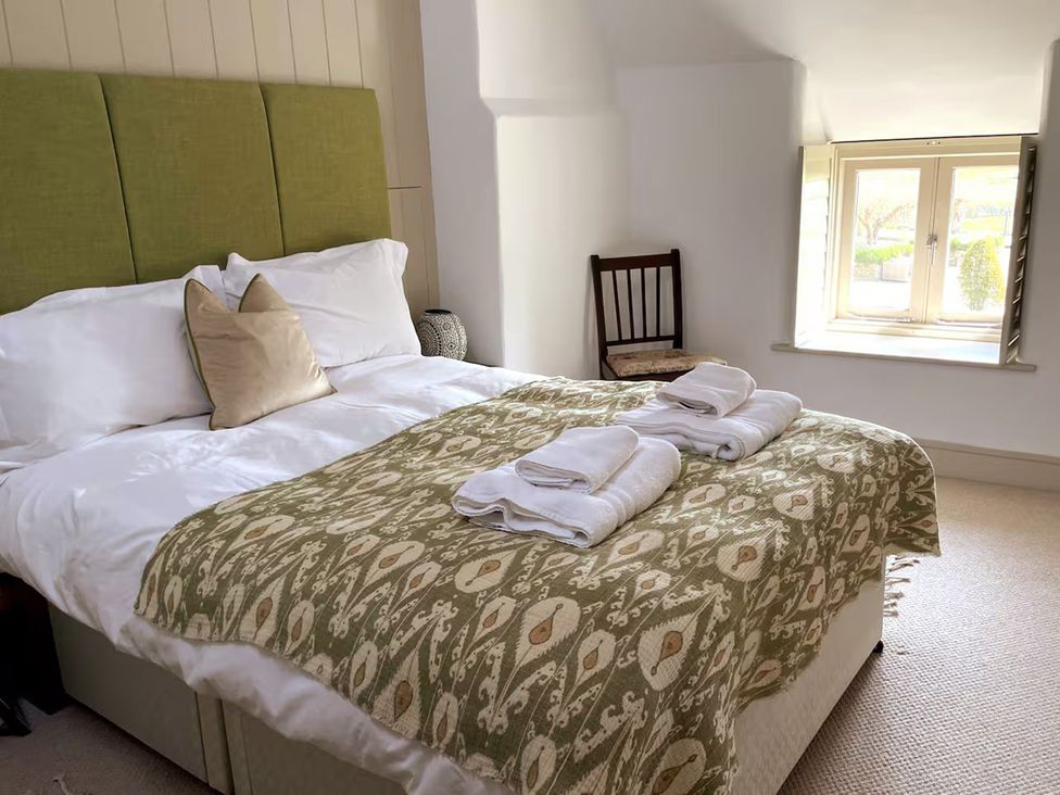 A bedroom with a bed and a chair at Stunning 6 Bedroom Riverside Barn Cotswold Mill in Ewan near Kemble