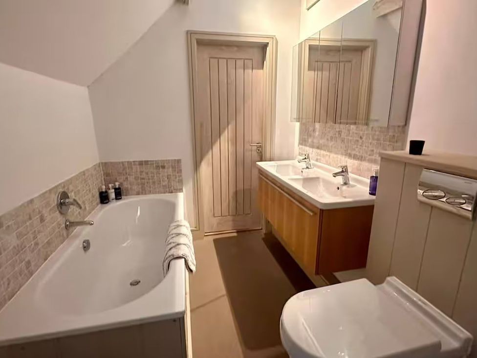 A bathroom with a bathtub and dual sinks at Stunning 6 Bedroom Riverside Barn Cotswold Mill Ewan near Kemble