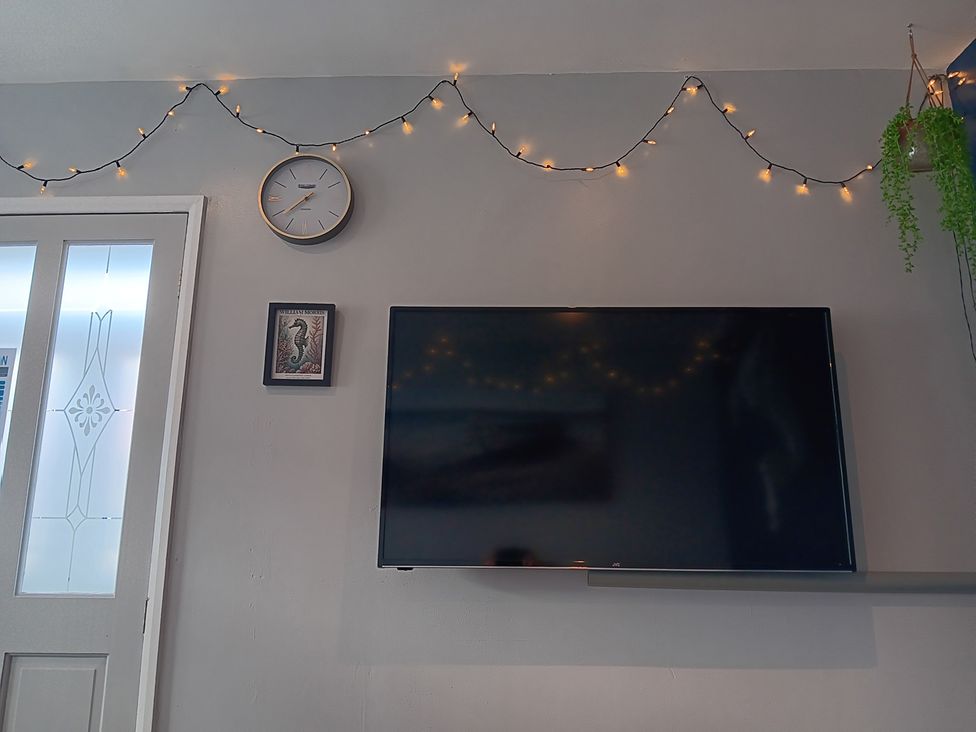 A living room with a TV and clock on the wall at Seahorse Chalet Sleeps 6 Pets Log Burner Beach in Bridlington