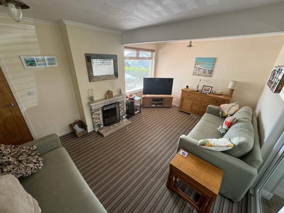 A living room with a fireplace and a television at Sea Side Stay 6 Pet Friendly Parking Garden in Rhosneigr