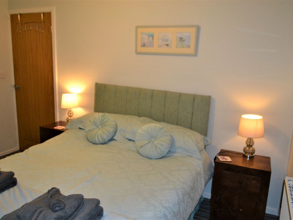A bedroom with a bed and bedside tables at Sea Side Stay 6 Pet Friendly Parking Garden Rhosneigr