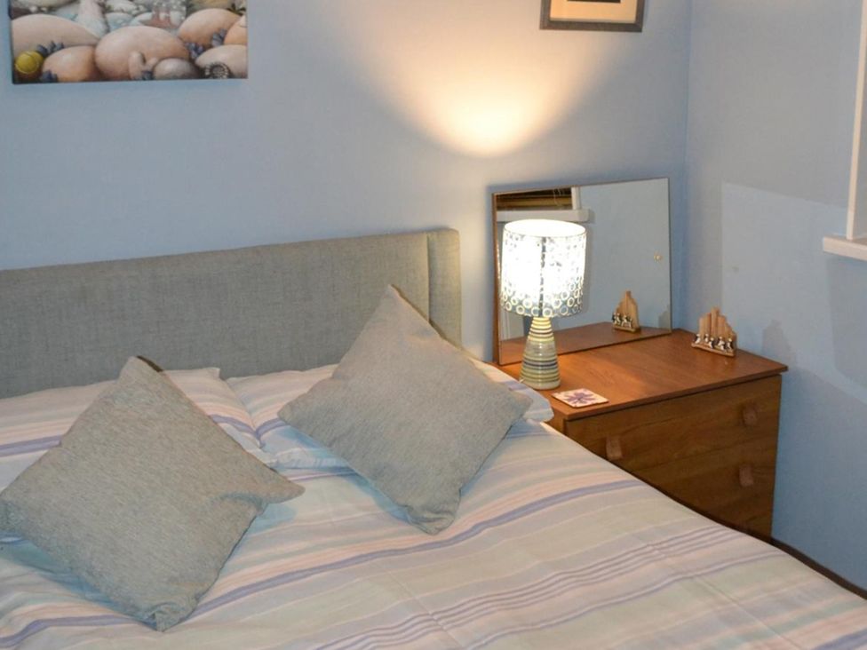 A bedroom with a bed, lamp, and mirror at Sea Side Stay 6 Pet Friendly Parking Garden Rhosneigr