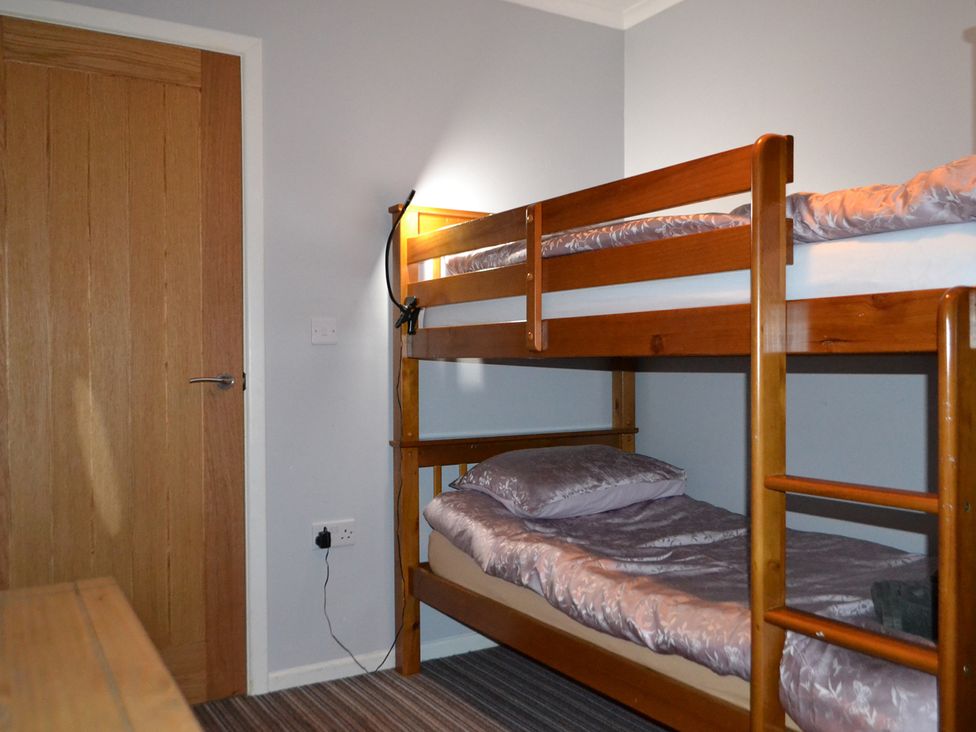 A bedroom with a bunk bed and door at Sea Side Stay 6 Pet Friendly Parking Garden Rhosneigr