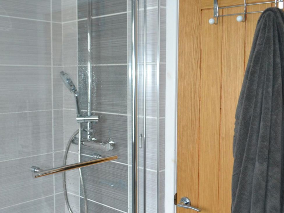 A bathroom with a shower and a towel hanging at Sea Side Stay 6 Pet Friendly Parking Garden in Rhosneigr
