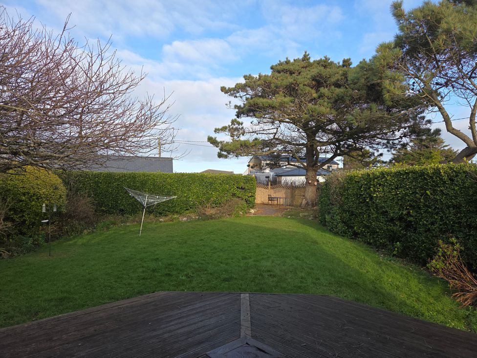 A garden with a tree and clothesline at Sea Side Stay 6 Pet Friendly Parking Garden Rhosneigr