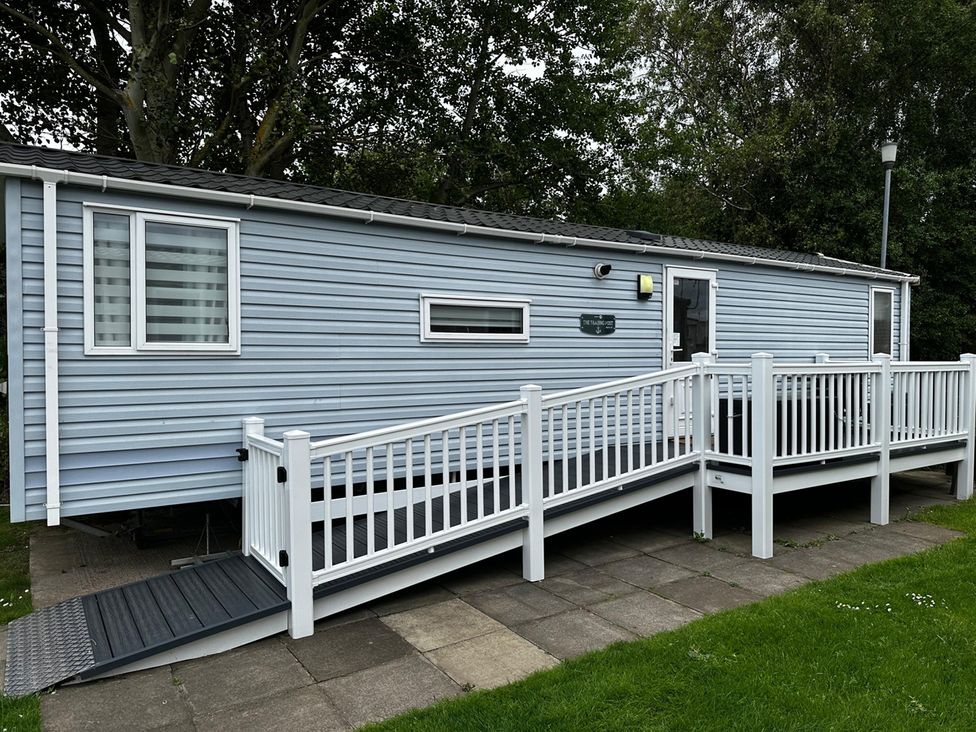 A mobile home with a deck and railings in an outdoor area