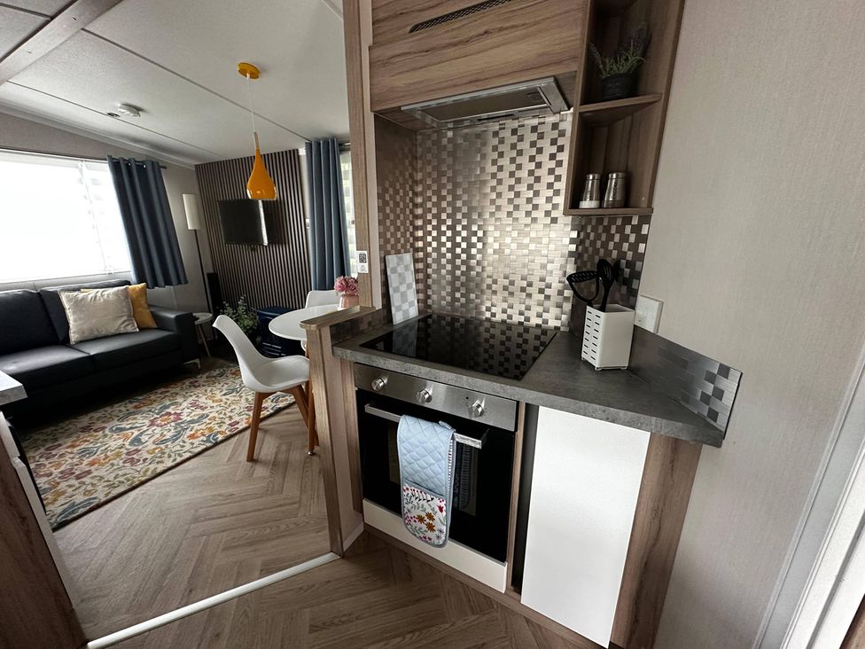 A kitchen with oven and cooktop next to a living area at a property
