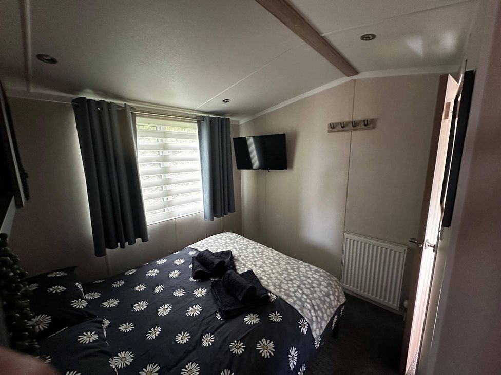 A bedroom with a bed, curtains, television, and hooks at the property