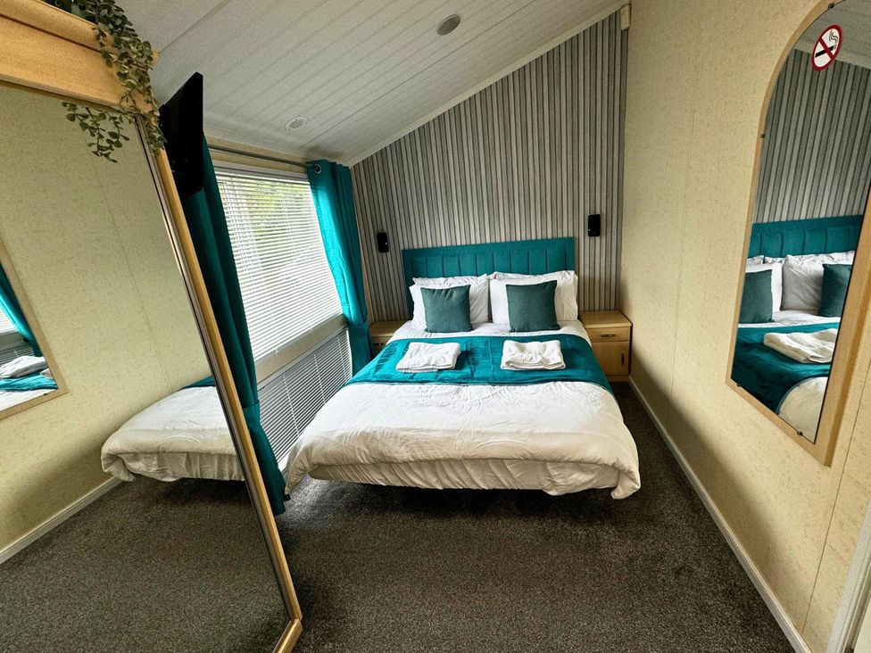 A bedroom with a bed and nightstand at Sunset 5 Southview Holiday Park Skegness