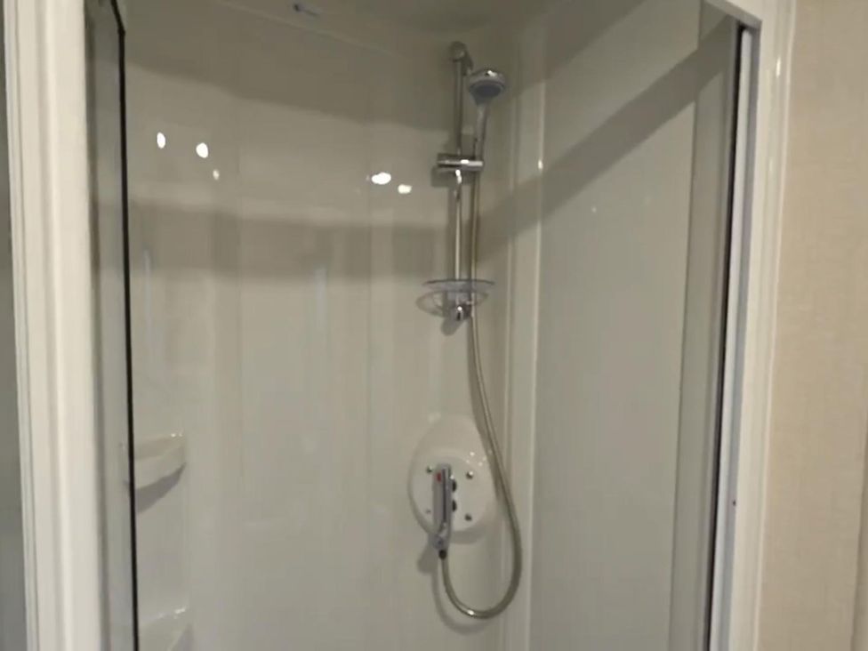 A shower enclosure with a handheld shower and wall-mounted fittings at the property