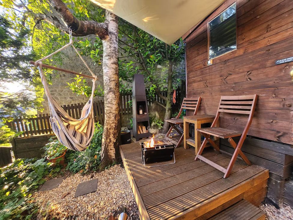 A garden with a hammock, wooden chairs, and a fire pit