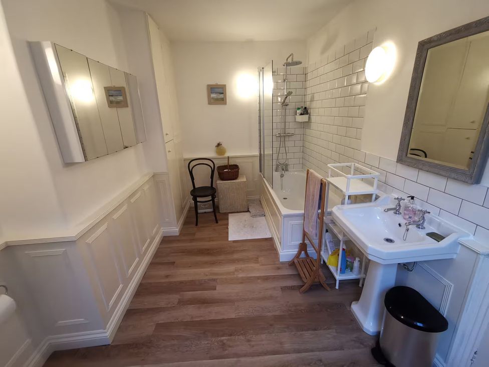 A bathroom with a bathtub, sink, and mirrors at a property
