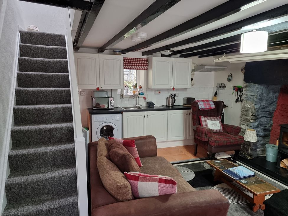 A living room with a sofa and kitchen area at a property