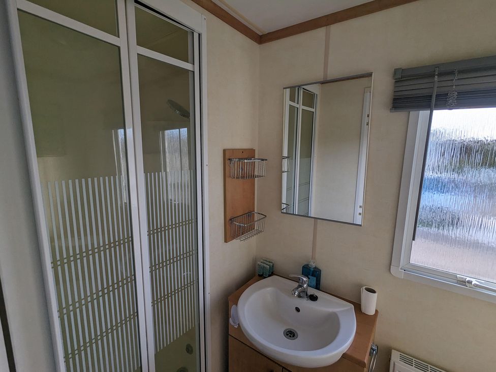 A bathroom with a shower, sink, and mirror at the property