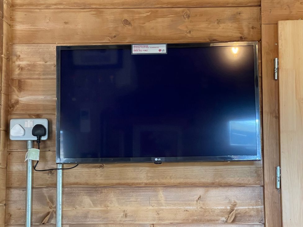 A TV mounted on a wooden wall with a power outlet at a property