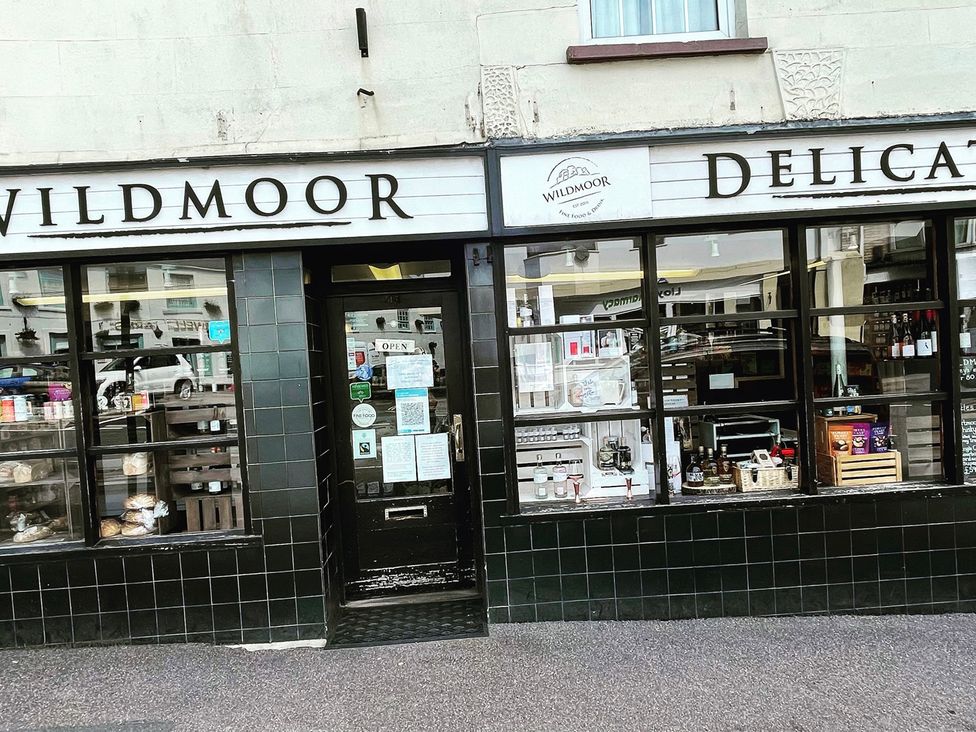 A storefront displaying food products and signage at Wildmoor Delicatessen in an urban area