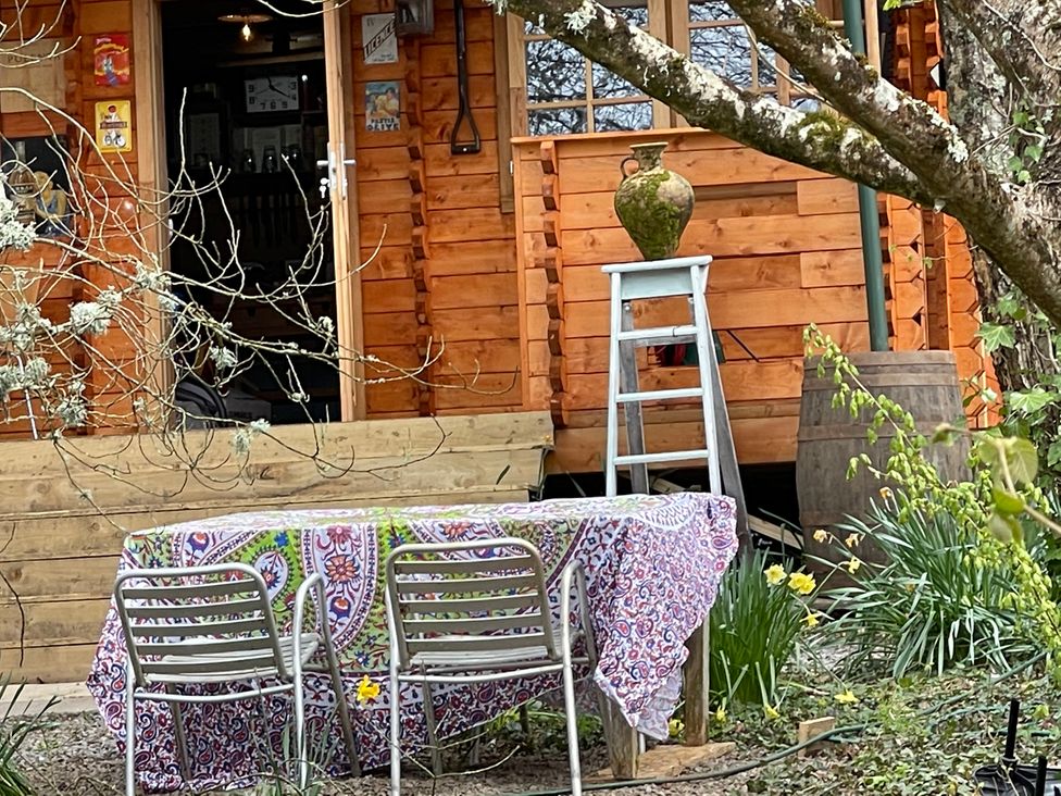 A table with chairs and a vase in front of a wooden cabin