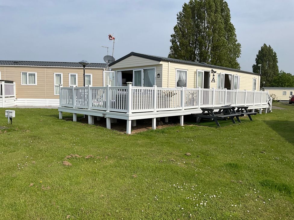 A mobile home with a deck and seating area at a holiday park